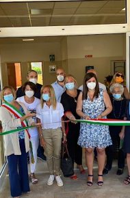 La Dirigente scolastica Maria Rossi taglia il nastro durante l'evento di inaugurazione della nuova ala scolastica insieme al corpo docenti e al Sindaco di Montebassiano. L'evento è stato ripreso dalle TV locali.