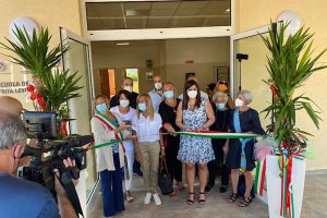 La Dirigente scolastica Maria Rossi taglia il nastro durante l'evento di inaugurazione della nuova ala scolastica insieme al corpo docenti e al Sindaco di Montebassiano. L'evento è stato ripreso dalle TV locali.